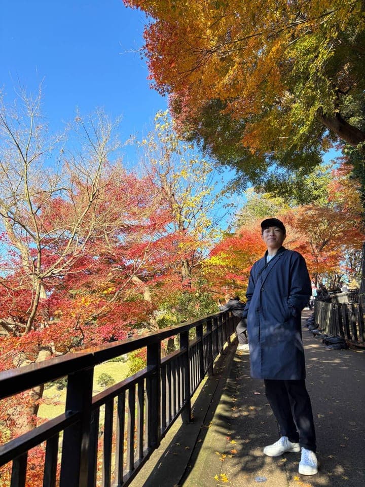 Tetsu Yamamoto standing under autumn leaves at Kenroku-en Garden in Kanazawa